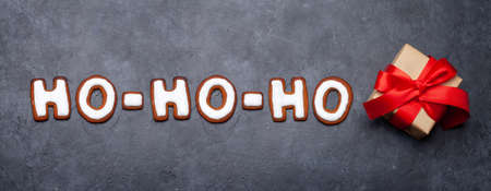 Christmas greeting card with homemade gingerbread HO-HO-HO cookies and gift box. Top view flat layの写真素材