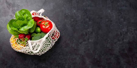 Eco friendly mesh shopping bag with fresh vegetables. Top view flat lay with copy space