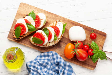Caprese salad with mozzarella, basil, fresh garden tomatoes on grilled toast. Top view flat layの写真素材