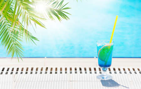 Tropical cocktail glass at the edge of swimming pool. With copy spaceの写真素材