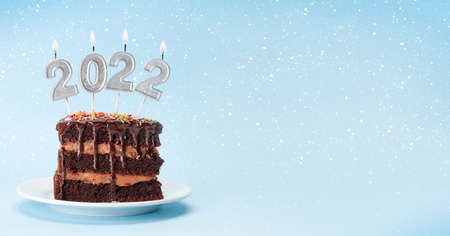 Christmas cake with number 2022 burning candles on a blue background with copy space for your xmas greetingsの写真素材