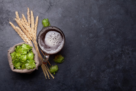 Lager beer mug, hops and wheat on old stone table. Top view flat lay with copy space