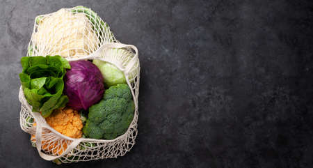 Eco friendly mesh shopping bag with fresh vegetables. Broccoli and cabbage. Top view flat lay with copy spaceの写真素材