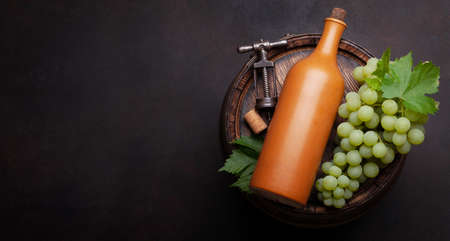 White grape, vintage corkscrew and wine bottle on old wooden wine barrel. Top view flat lay with copy spaceの写真素材