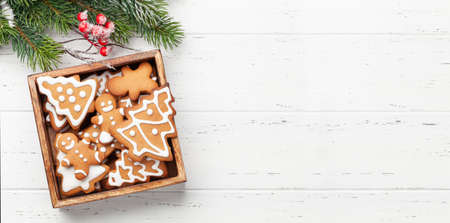 Christmas card with gingerbread cookies over wooden background. Top view flat lay with space for...