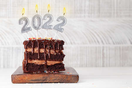 Christmas chocolate cake with number 2022 burning candles with copy space for your xmas greetings