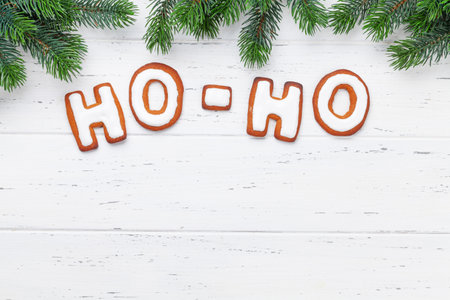 Christmas greeting card with homemade gingerbread HO-HO text and fir tree. Top view flat lay with space for your greetingsの写真素材