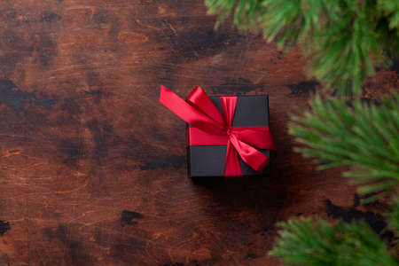 Christmas gift box with red bow and fir tree. Top view flat lay with space for your greetingsの写真素材