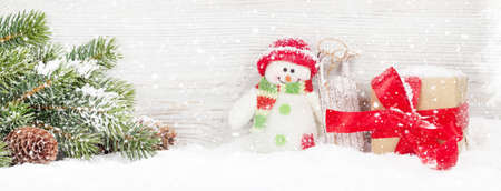 Christmas snowman toy, gift box and fir tree branch. Xmas greeting cardの写真素材