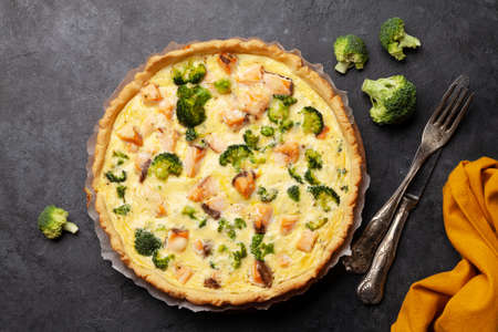 Homemade fish pie. Open faced salmon and broccoli pie on dark kitchen table. Top view flat layの写真素材