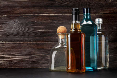 Various hard liquor bottles. Gin, vodka, tequila and whiskey in front of wooden wall with copy spaceの写真素材