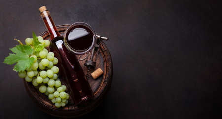 White grape, vintage corkscrew and wine glass and bottle on old wooden wine barrel. Top view flat...