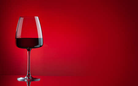 Red wine glass over red background with copy spaceの写真素材