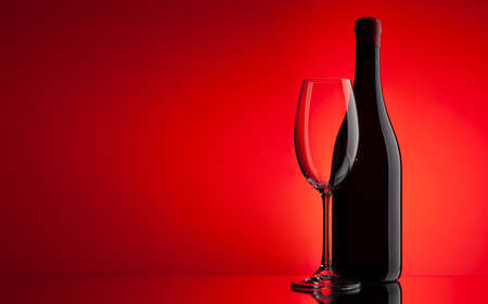 Red wine glass and bottle over red background with copy spaceの写真素材