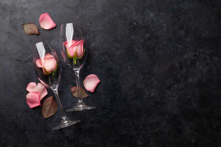 Champagne glasses and rose flower petals. Valentines day greeting card with space for your greetings. Top view flat layの写真素材
