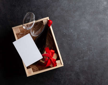 Valentines day gift box with red wine bottle. Top view flat lay with greeting card for your...