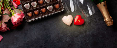 Champagne bottle, rose flowers and heart shape chocolate. Valentines day greeting card with gift box and space for your greetings. Top view flat layの写真素材