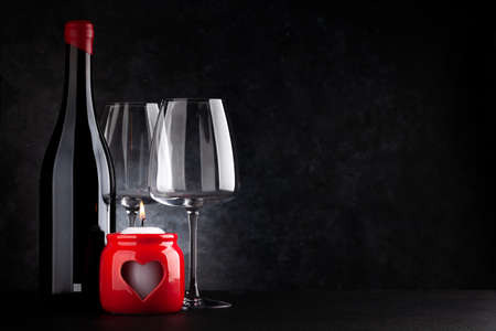Valentines day burning candle and red wine bottle. With space for your greetingsの写真素材