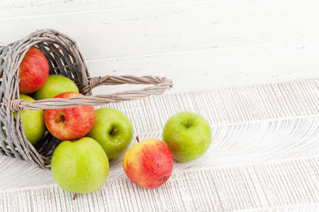 Fresh ripe apples in basket on wooden table. Red and green apple fruits. With copy spaceの写真素材
