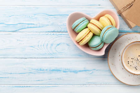Homemade macaroons in heart shaped bowl and coffee cup. Top view flat lay with space for your Valentines day greetingsの写真素材