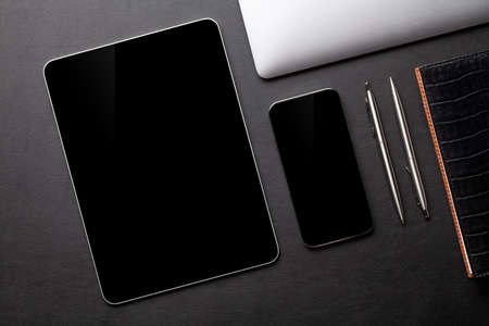 Tablet and smartphone with blank screen on desk. Top view flat lay with copy space