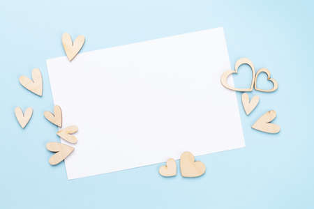 Valentines day wooden hearts decor over blue background and blank greeting card with copy space. Top view flat layの写真素材