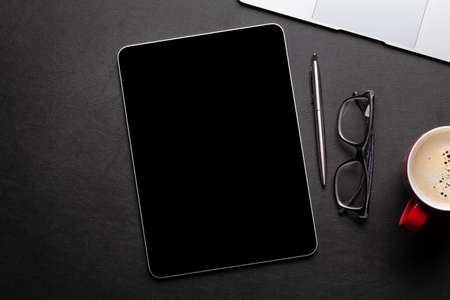 Tablet with blank screen on desk, coffee cup and office supplies. Top view flat lay with copy spaceの写真素材