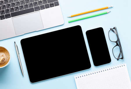 Tablet and smartphone with blank screen on desk. Top view flat lay with copy space