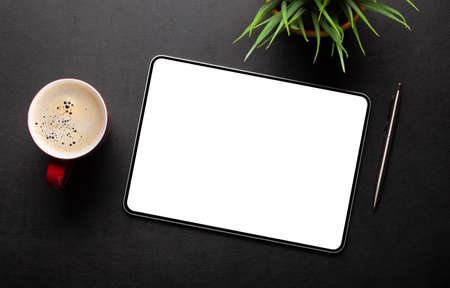 Tablet with blank screen on desk, coffee cup and office supplies. Top view flat lay with copy spaceの写真素材