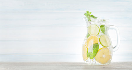 Lemonade pitcher with lemon, mint and ice cubes. With copy space