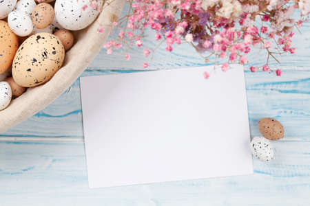 Easter greeting card, easter eggs and flowers. Top view flat lay with copy space