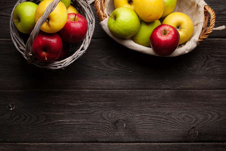 Colorful ripe apple fruits in basket on wooden table. Top view flat lay with copy spaceの写真素材