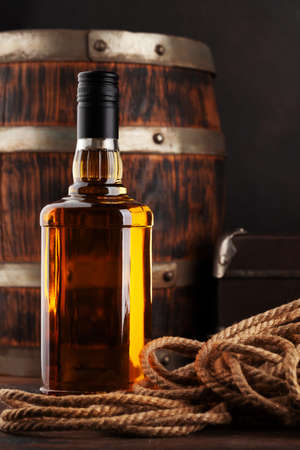 Bottle with cognac, whiskey or golden rum. In front of old wooden barrel with copy spaceの写真素材