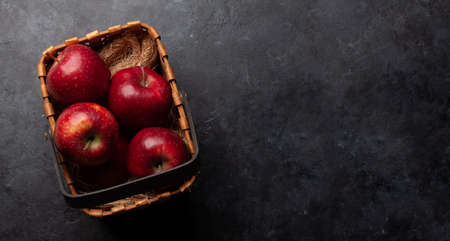 Red ripe apple fruits in basket on wooden table. Top view flat lay with copy spaceの写真素材