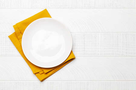 Empty plate over towel on wooden table. Top view flat lay with copy space. Template or mockup for your mealsの写真素材