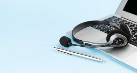 Headset over laptop on blue background with copy space. Template for service or supportの写真素材