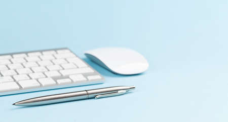 Pc keyboard, mouse and pen on blue background with copy spaceの写真素材