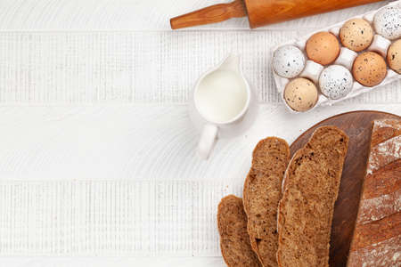 Sliced homemade bread and ingredients on wooden table. Flat lay with copy spaceの写真素材