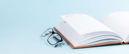 Notepad and glasses over blue background with copy spaceの写真素材