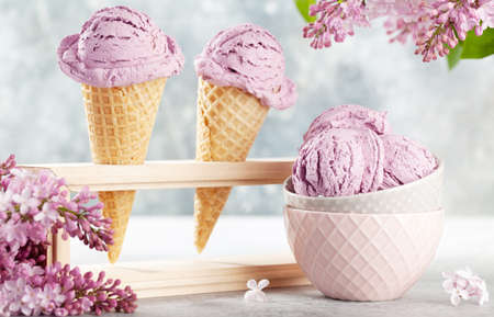 Berry ice cream sundae in waffle cones and lilac flowers
