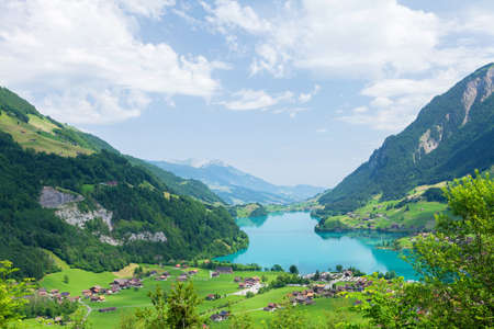 Panoramic view of lake, countryside, green alpine meadows and the Alps mountains in Switzerlandの写真素材
