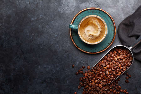 Roasted coffee beans in scoop and cup of espresso. Flat lay on stone table with copy spaceの写真素材