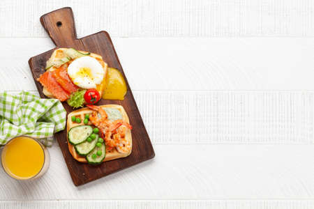 Breakfast waffles with fried eggs, salmon, bacon, cucumber and prawns. Top view flat lay with coffee, orange juice and copy spaceの写真素材