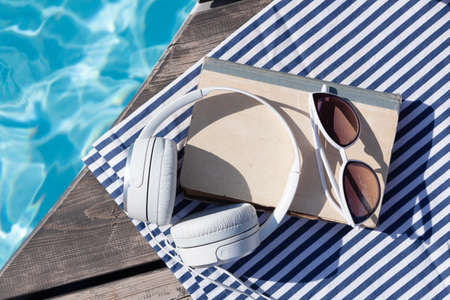 Book and headphones near swimming pool. summer holiday. Flat lay with copy spaceの写真素材