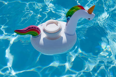 Drink cup in inflatable unicorn toy in swimming pool. summer vacation and holiday conceptの写真素材