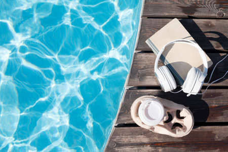 Book and headphones near swimming pool. summer holiday. Flat lay with copy spaceの写真素材