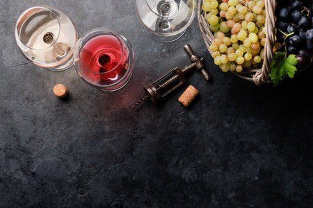 White, rose and red wine glasses and grapes. Flat lay with copy space