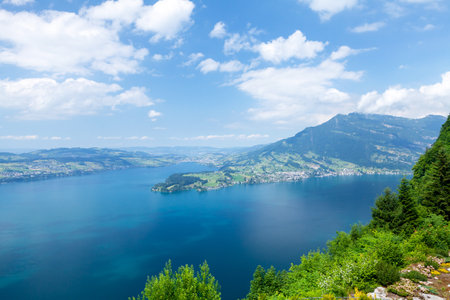 Panoramic view of lake, countryside, green alpine meadows and the Alps mountains in Switzerlandの写真素材