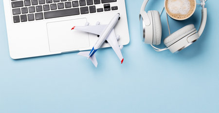 Travel and online booking concept. Laptop and airplane on blue desk with copy space