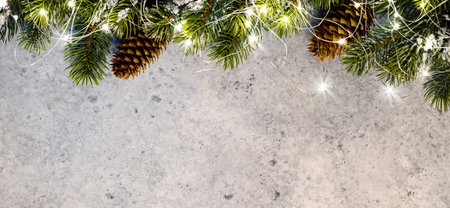Christmas glowing garland and fir tree branches on stone background with copy space